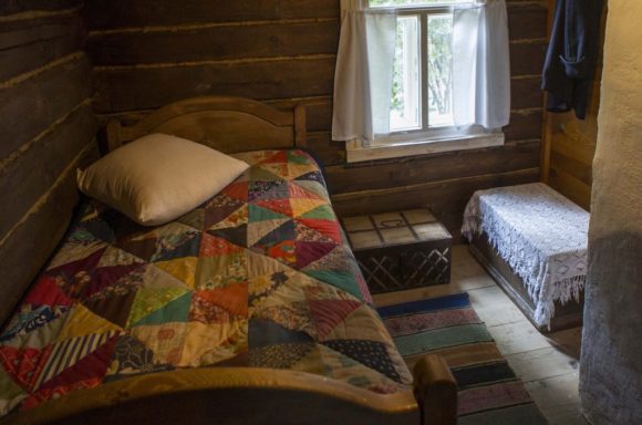 В прихожей — уголок поэта. У окна — деревянная кровать с одеялом из пёстрых лоскутов. Рядом — сундучок, хранивший книги любимых писателей.